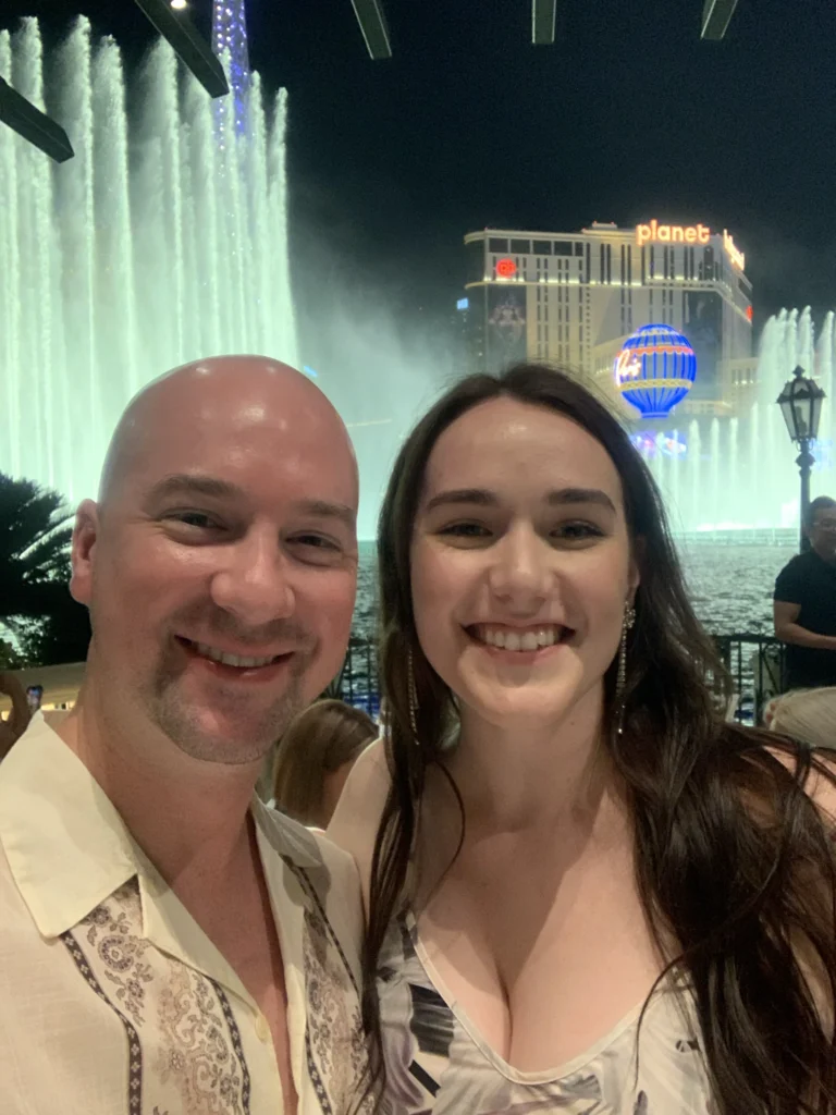 A couple is taking a selfie in front of the Bellagio Fountains in Las Vegas